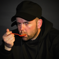 man eating in black court and wearing a hat